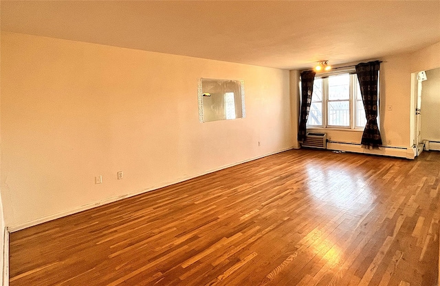 empty room featuring a baseboard heating unit, a wall unit AC, and hardwood / wood-style flooring