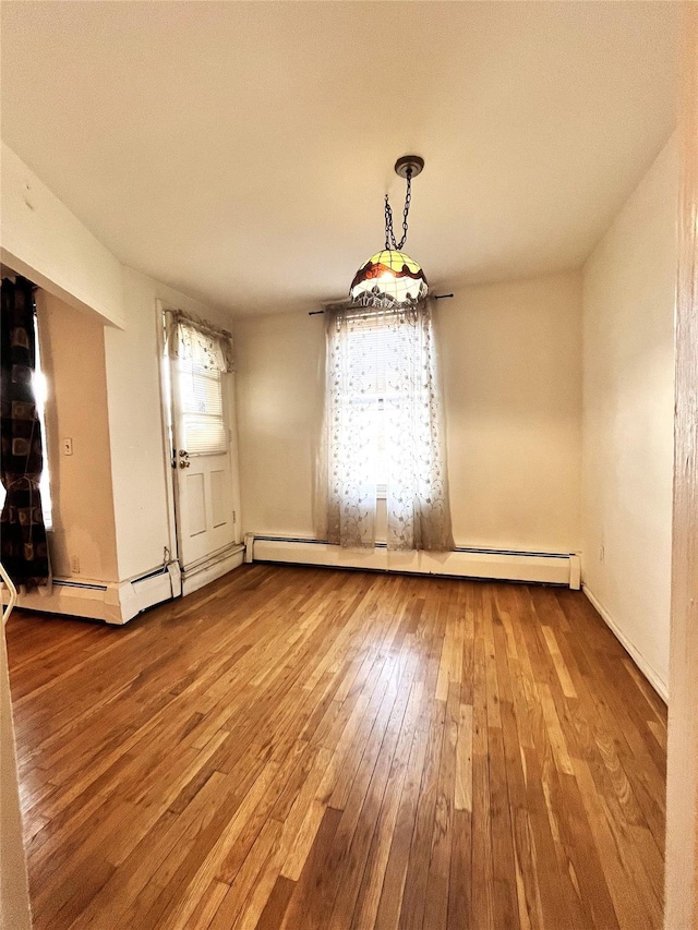 unfurnished dining area featuring a baseboard radiator and hardwood / wood-style floors