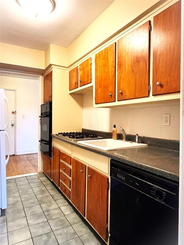 kitchen with light tile patterned floors, sink, and black appliances