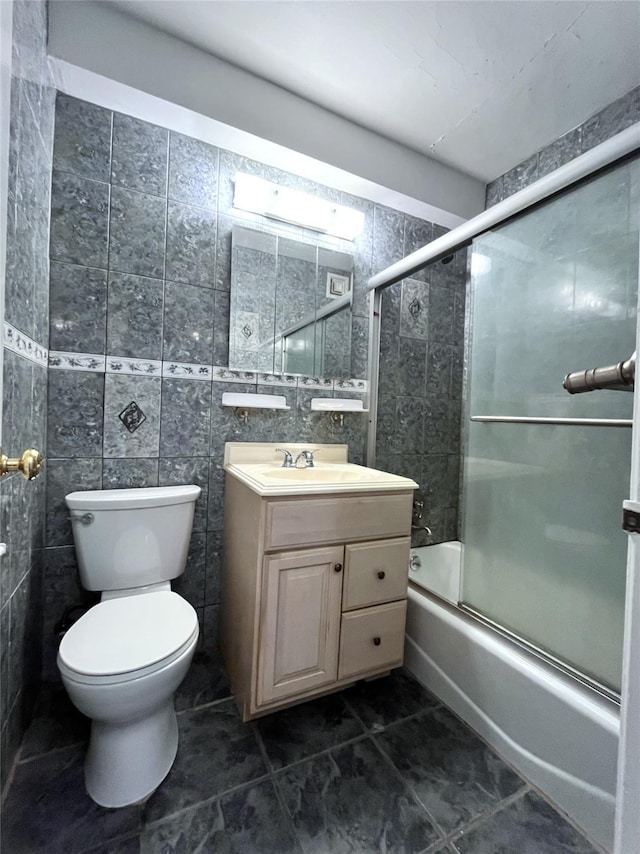 full bathroom featuring toilet, tile walls, vanity, and shower / bath combination with glass door