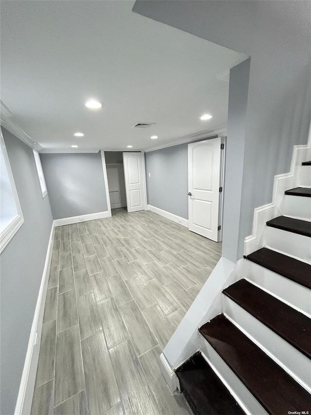 basement featuring light wood-type flooring and ornamental molding