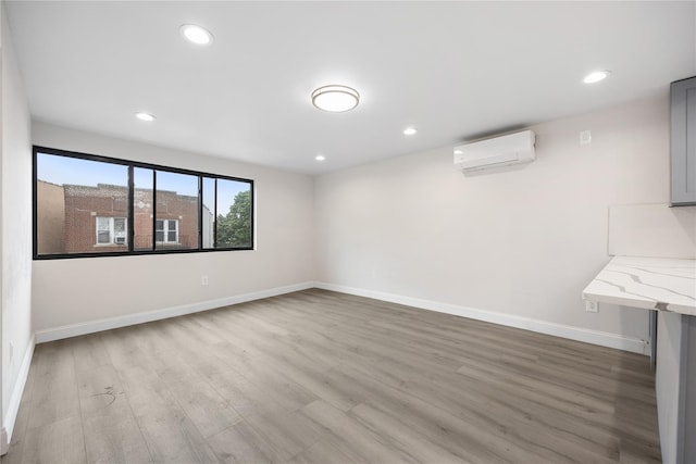 interior space with a wall mounted AC and light hardwood / wood-style flooring