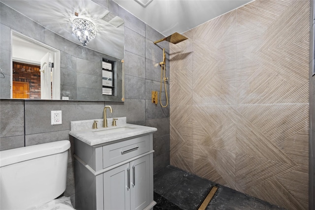 bathroom featuring tile walls, toilet, vanity, and a tile shower