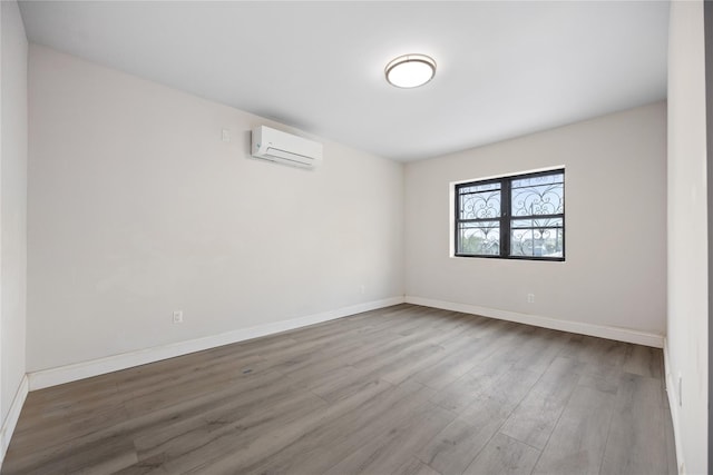 empty room featuring a wall mounted AC and wood-type flooring