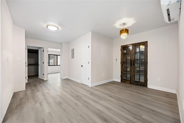 unfurnished room with electric panel, a chandelier, and light wood-type flooring