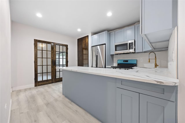 kitchen featuring stainless steel appliances, french doors, light hardwood / wood-style floors, sink, and gray cabinetry