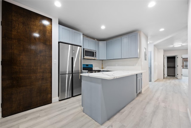 kitchen featuring stainless steel appliances, light hardwood / wood-style floors, and light stone countertops