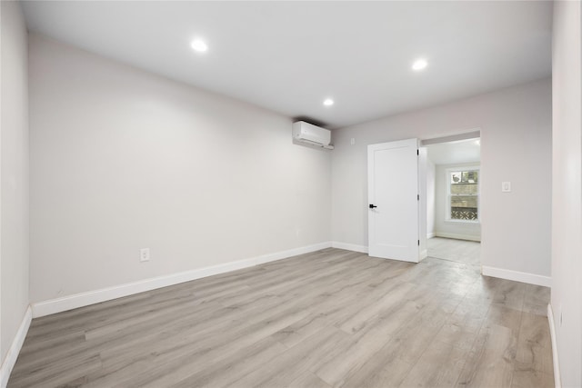 empty room with light wood-type flooring and an AC wall unit