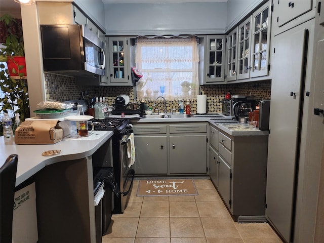 kitchen featuring light tile patterned floors, backsplash, sink, and gray cabinets