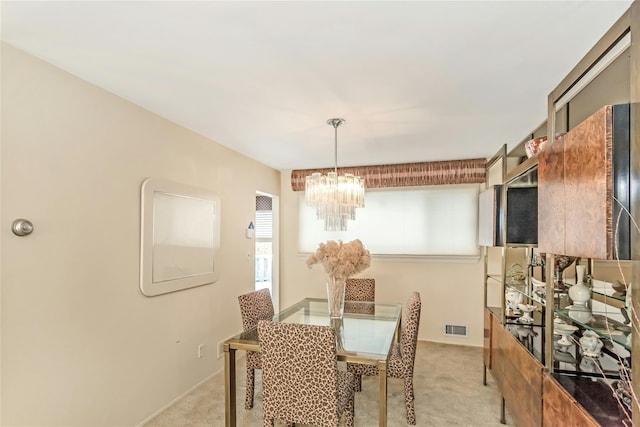 dining space with light colored carpet and a notable chandelier