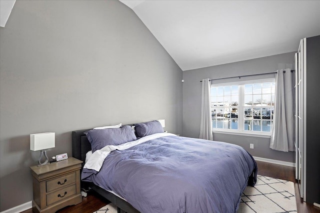 bedroom featuring light wood-type flooring, vaulted ceiling, and a water view