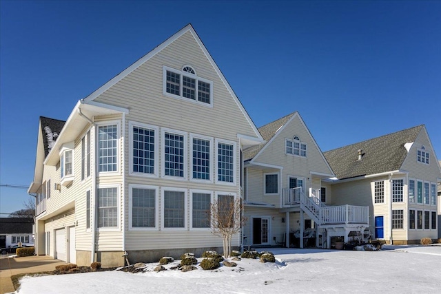 snow covered rear of property with a garage