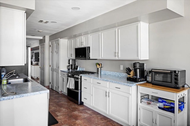 kitchen with range with two ovens, light countertops, white cabinets, and a sink