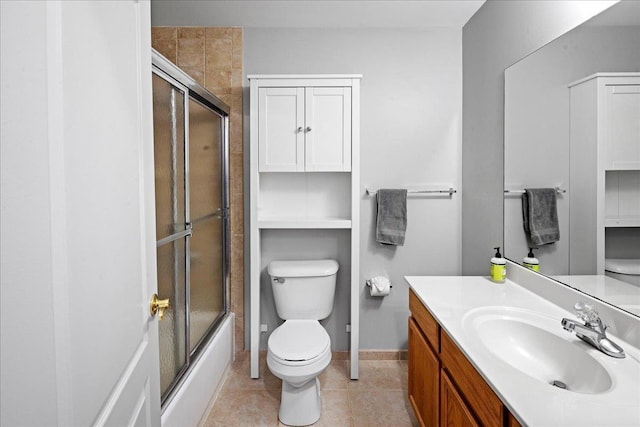 bathroom with toilet, enclosed tub / shower combo, vanity, tile patterned flooring, and baseboards