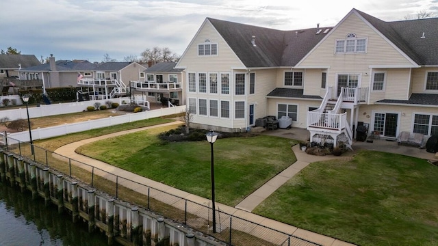 rear view of house with a water view, a fenced backyard, a lawn, and a patio