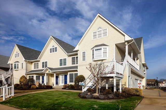 traditional-style house featuring driveway, a front yard, stairway, a porch, and a garage