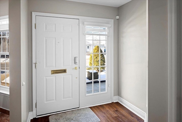 doorway to outside featuring baseboards and dark wood-style flooring