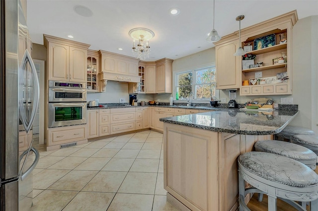 kitchen with appliances with stainless steel finishes, dark stone countertops, hanging light fixtures, a kitchen breakfast bar, and kitchen peninsula