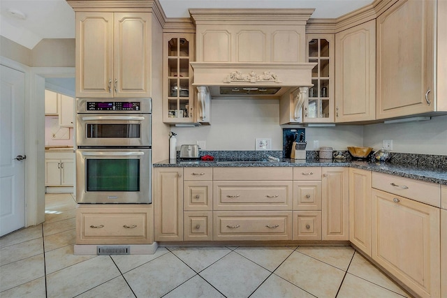 kitchen featuring light brown cabinetry, double oven, and light tile patterned floors