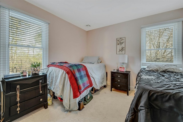 bedroom with multiple windows and light carpet