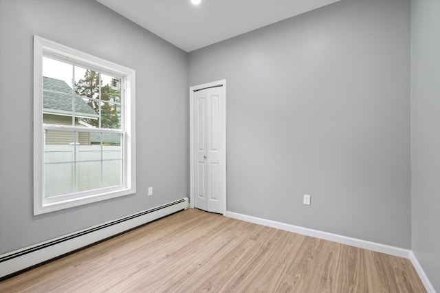 empty room with light hardwood / wood-style flooring and a baseboard radiator