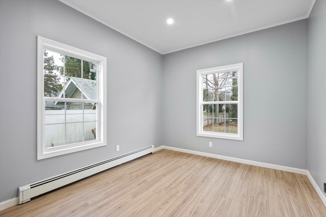 empty room with a baseboard heating unit, plenty of natural light, and light wood-type flooring