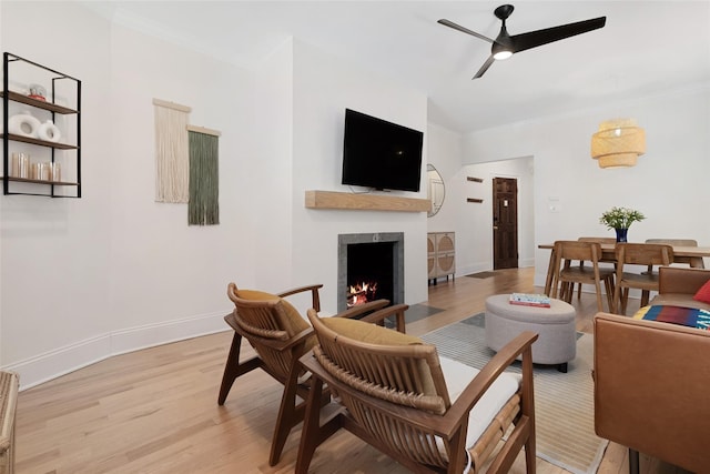 living room featuring ceiling fan, ornamental molding, and light wood-type flooring