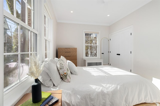 bedroom with crown molding, radiator heating unit, and wood-type flooring