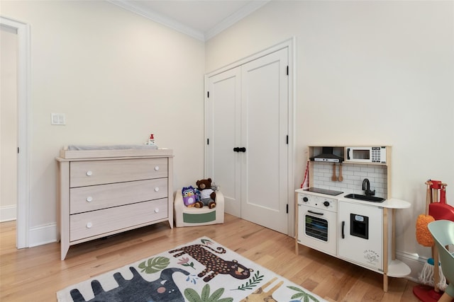 game room featuring ornamental molding and light hardwood / wood-style floors