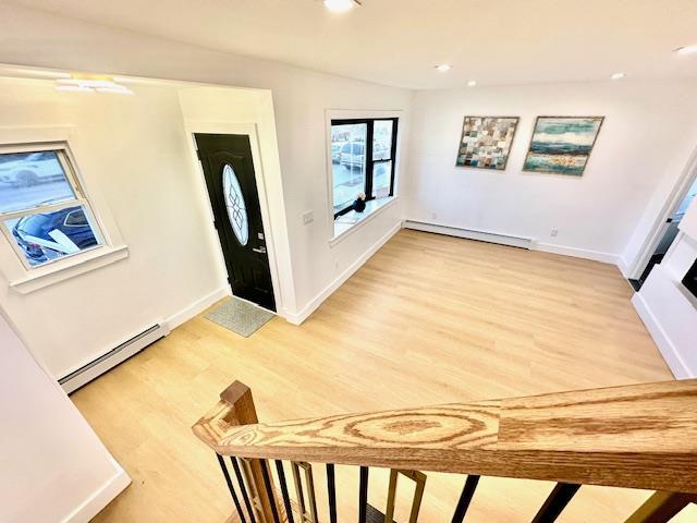 entryway with lofted ceiling, wood-type flooring, and a baseboard heating unit