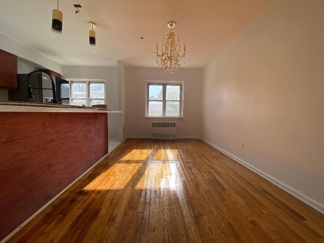 interior space featuring an inviting chandelier, radiator heating unit, and wood-type flooring