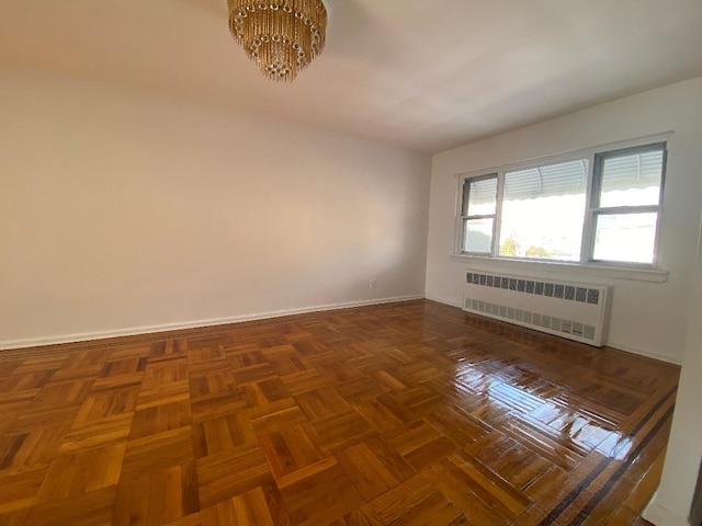 unfurnished room featuring radiator, a notable chandelier, and dark parquet floors