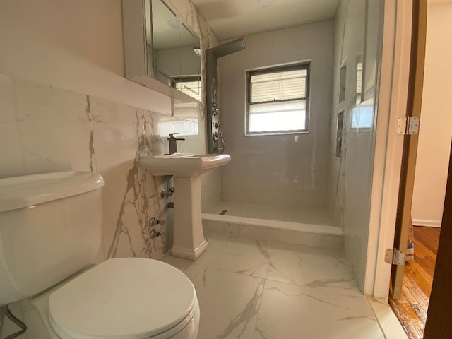 bathroom featuring tiled shower and toilet