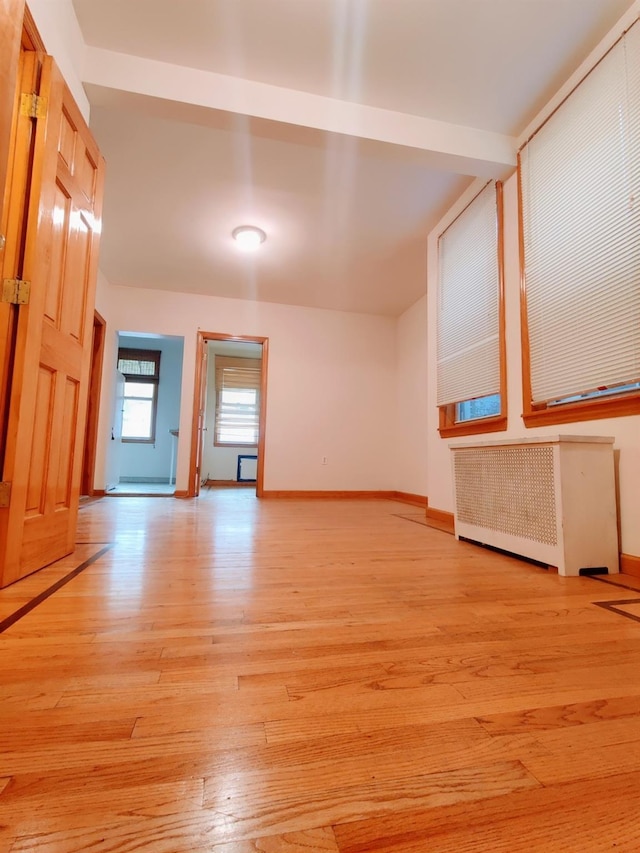 unfurnished living room featuring radiator and light wood-type flooring