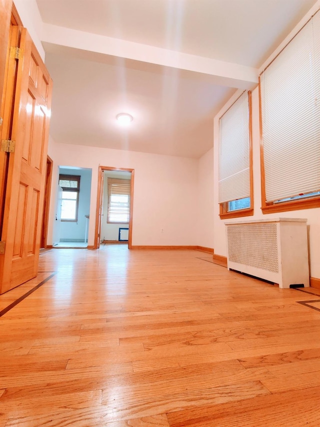 unfurnished room featuring radiator and light wood-type flooring