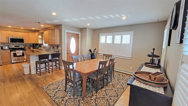 dining space featuring light wood-type flooring, baseboard heating, and sink