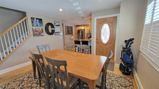 dining space with light hardwood / wood-style floors, baseboard heating, and a healthy amount of sunlight