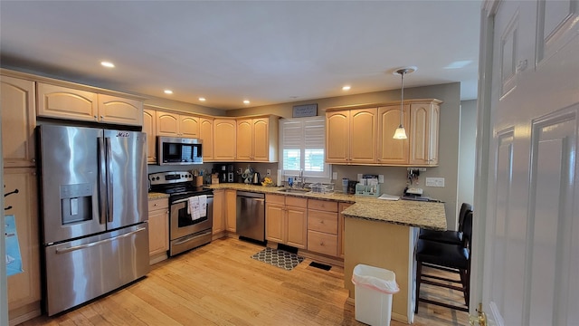 kitchen with light stone countertops, a kitchen bar, stainless steel appliances, hanging light fixtures, and kitchen peninsula