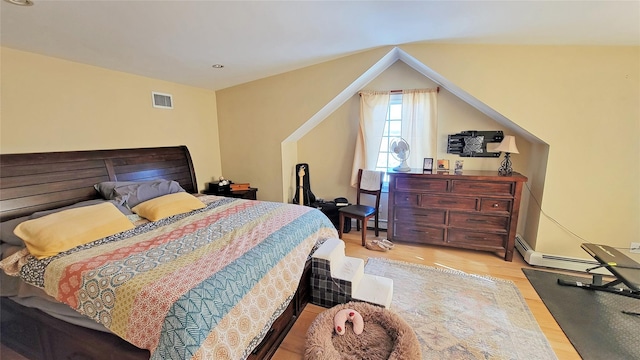 bedroom featuring a baseboard heating unit and light hardwood / wood-style flooring