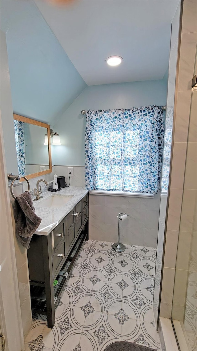 bathroom with tile walls, walk in shower, vanity, and vaulted ceiling