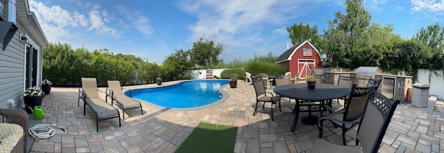 view of swimming pool featuring a patio area, a storage shed, and area for grilling