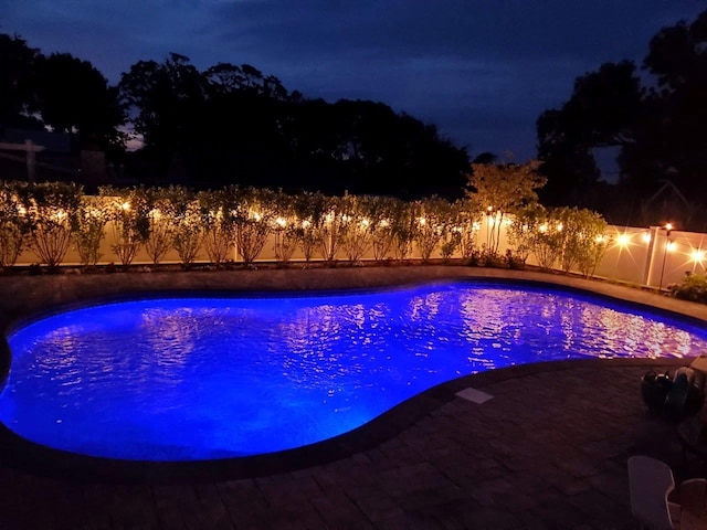 view of pool at twilight