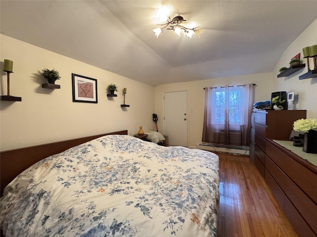 bedroom with dark wood-type flooring, lofted ceiling, ceiling fan with notable chandelier, and a baseboard radiator