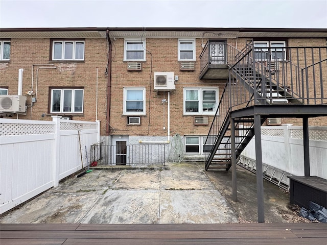 rear view of house featuring a wall unit AC