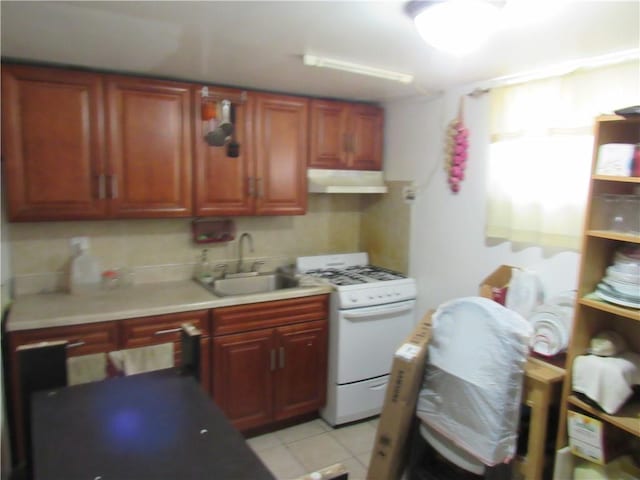 kitchen featuring sink, light tile patterned floors, and white gas range