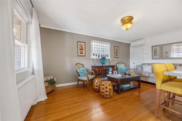 living room with a wall unit AC, radiator, crown molding, and light hardwood / wood-style flooring