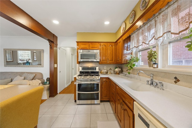 kitchen featuring light tile patterned floors, backsplash, sink, and stainless steel appliances