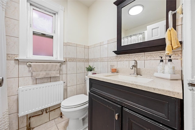 bathroom featuring radiator heating unit, tile patterned floors, vanity, tile walls, and toilet