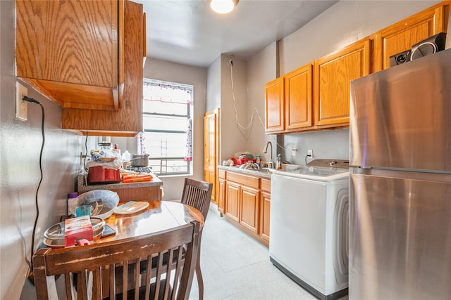 kitchen with washer / clothes dryer, stainless steel fridge, and sink