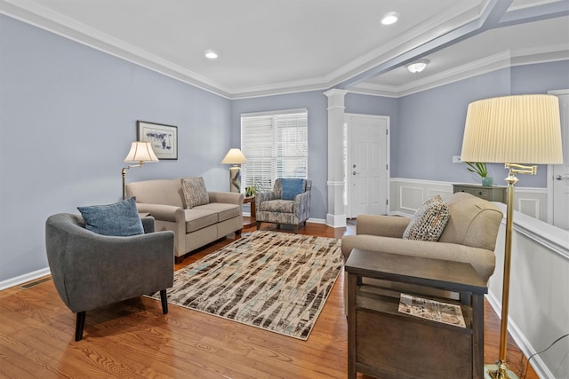 living room featuring hardwood / wood-style floors, ornamental molding, and ornate columns